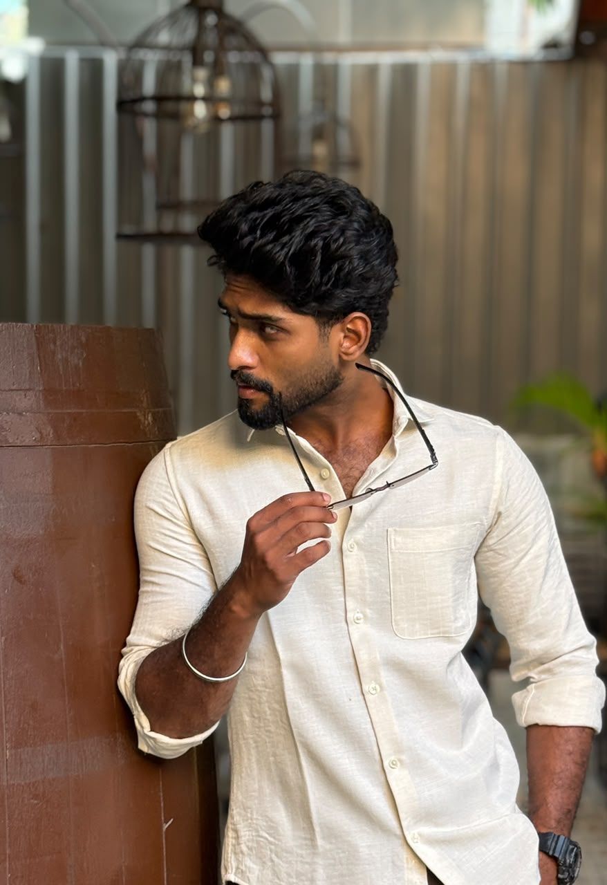Eswar in a white linen shirt, holding his glasses