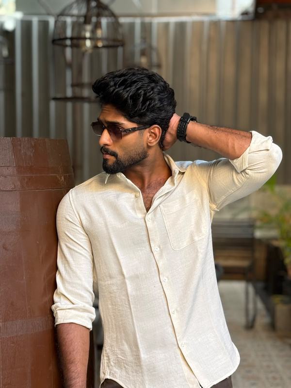 Eswar in a white linen shirt and tinted sunglasses, hand behind his head