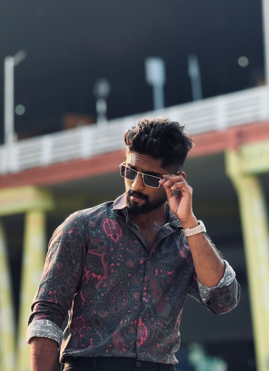 Eswar in a paisley shirt and sunglasses, looking down
