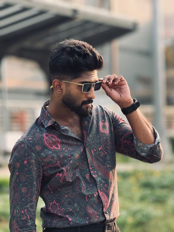 Eswar adjusting gold-rimmed sunglasses, in a paisley shirt